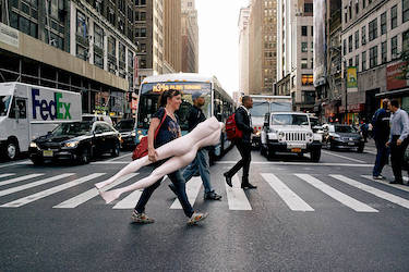 Woman carrying mannequin across major intersection in Garment District