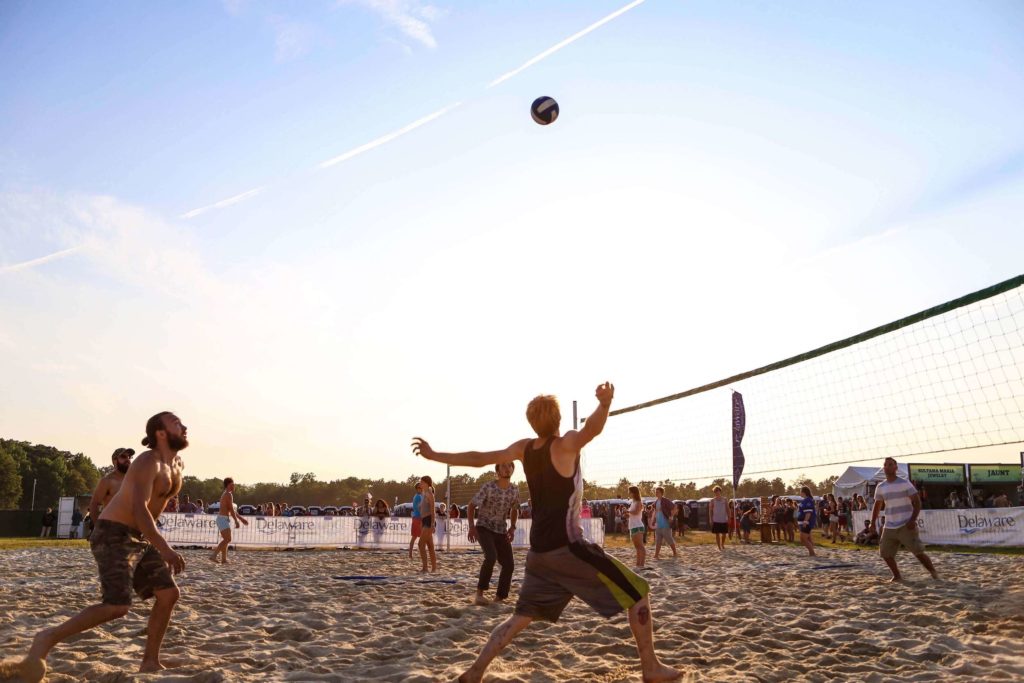 A group of people playing volleyball on the beach